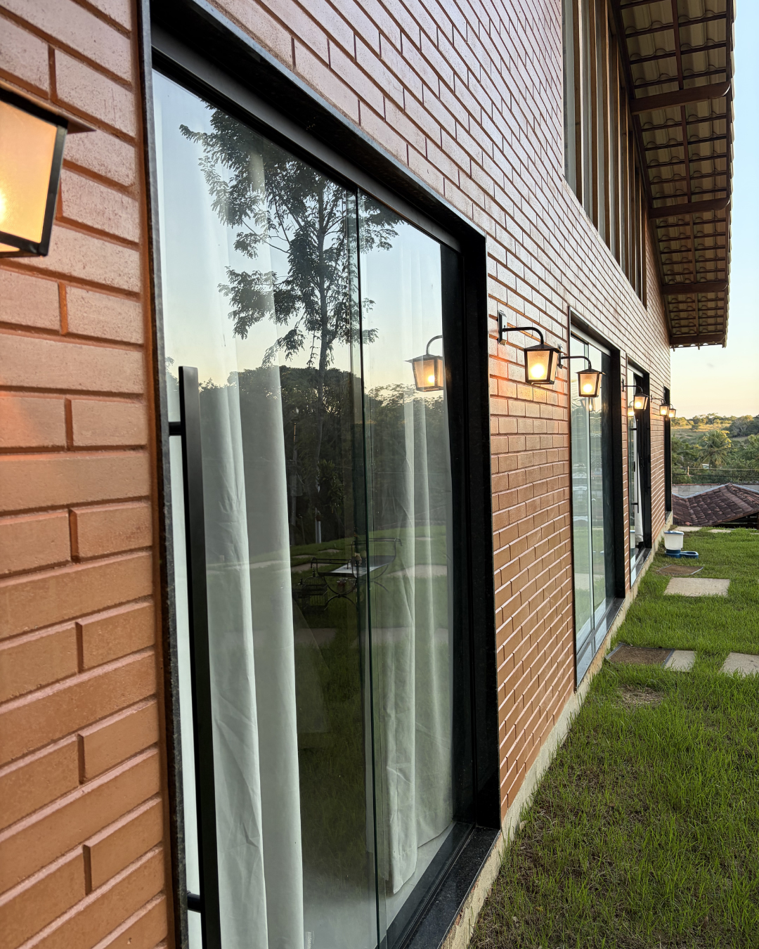 Fachada em tijolo aparente com esquadrias e arandelas